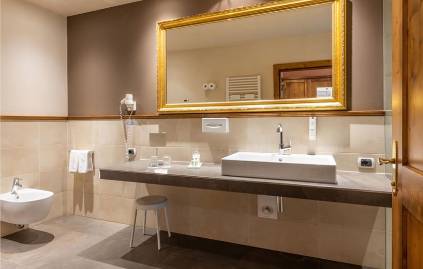 Modernes Badezimmer mit Bidet, Waschbecken und einem Spiegel in einem goldenen Rahmen - Doppelzimmer Landro Lodge